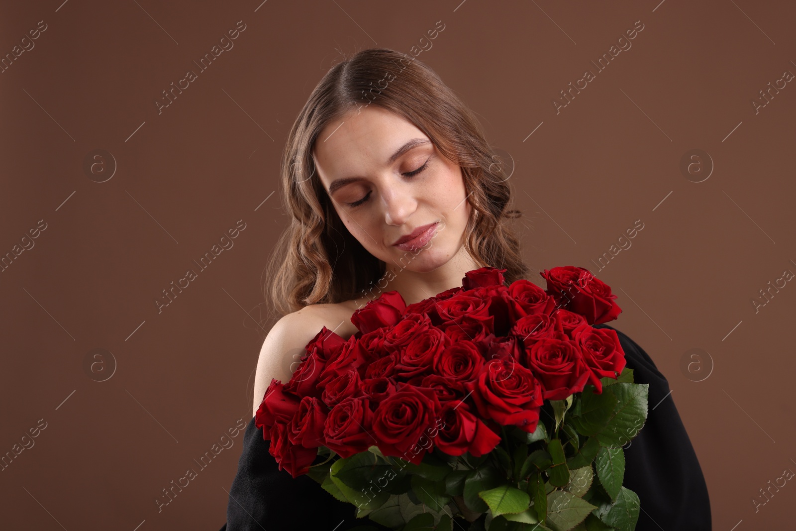 Photo of Beautiful woman with bouquet of roses on brown background