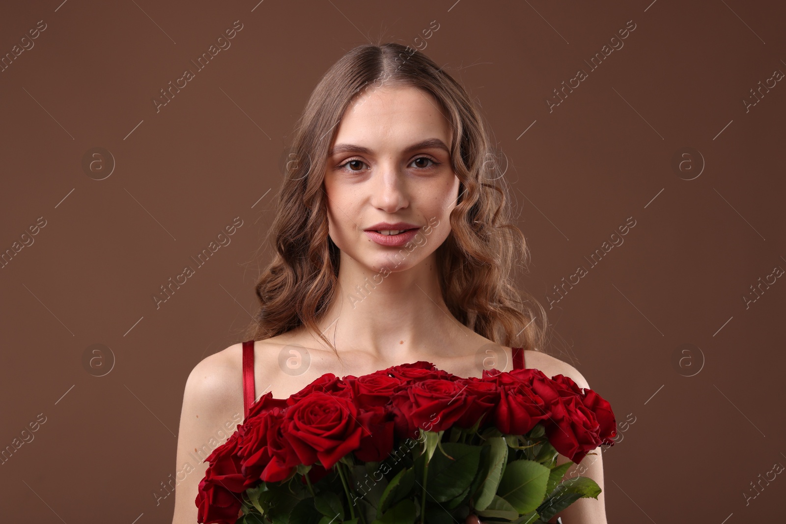 Photo of Beautiful woman with bouquet of roses on brown background