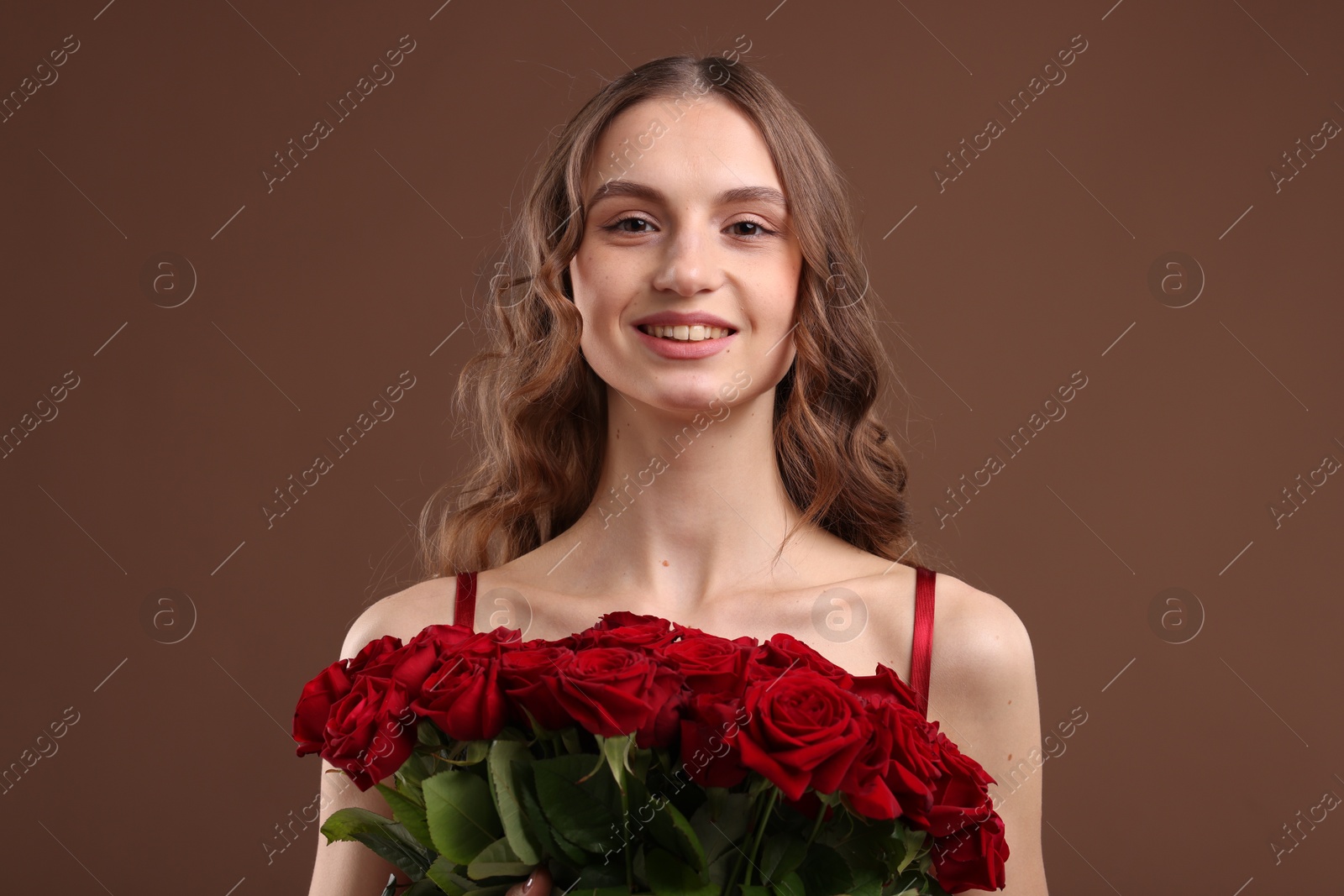 Photo of Smiling woman with bouquet of roses on brown background