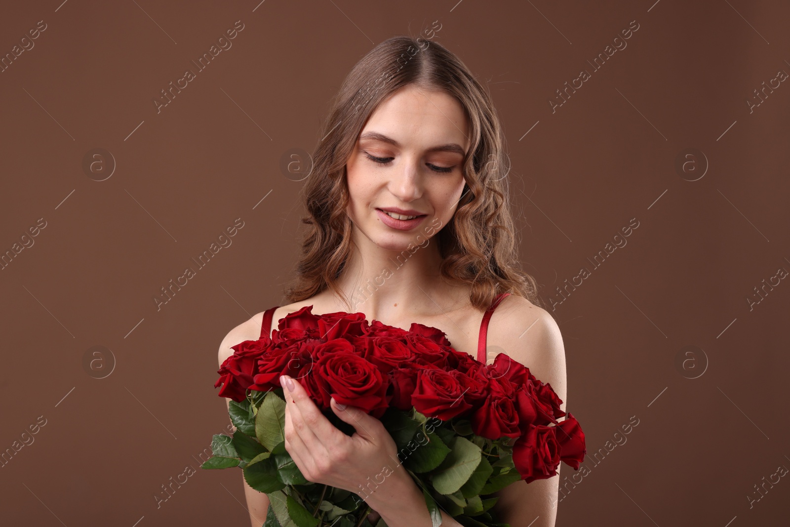 Photo of Smiling woman with bouquet of roses on brown background