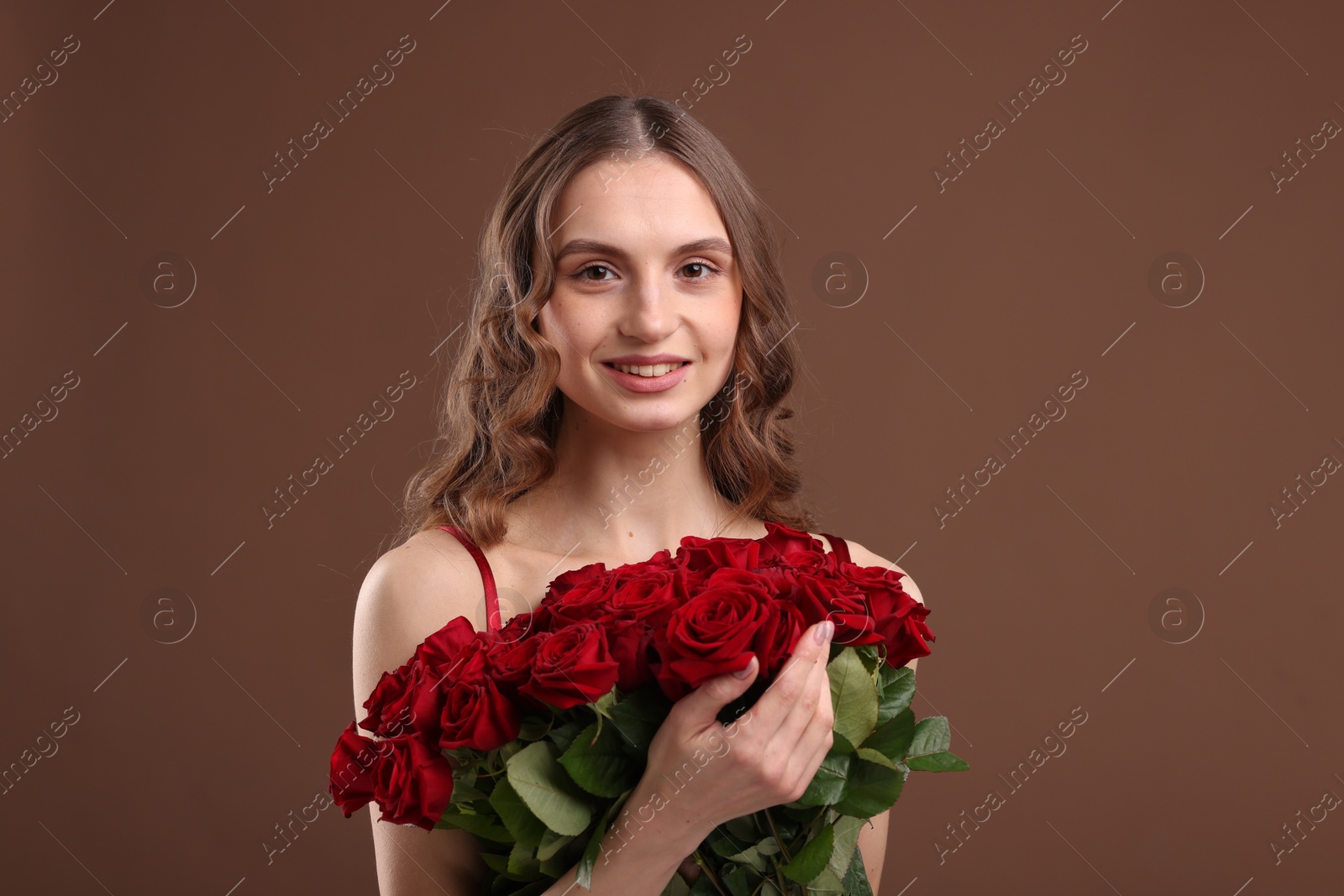 Photo of Smiling woman with bouquet of roses on brown background