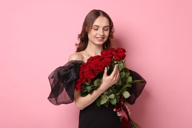 Photo of Smiling woman with bouquet of roses on pink background