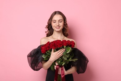 Smiling woman with bouquet of roses on pink background