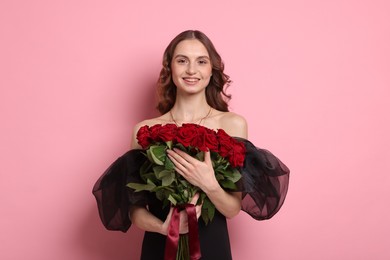 Photo of Smiling woman with bouquet of roses on pink background