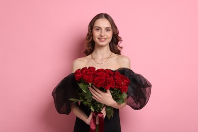 Photo of Smiling woman with bouquet of roses on pink background