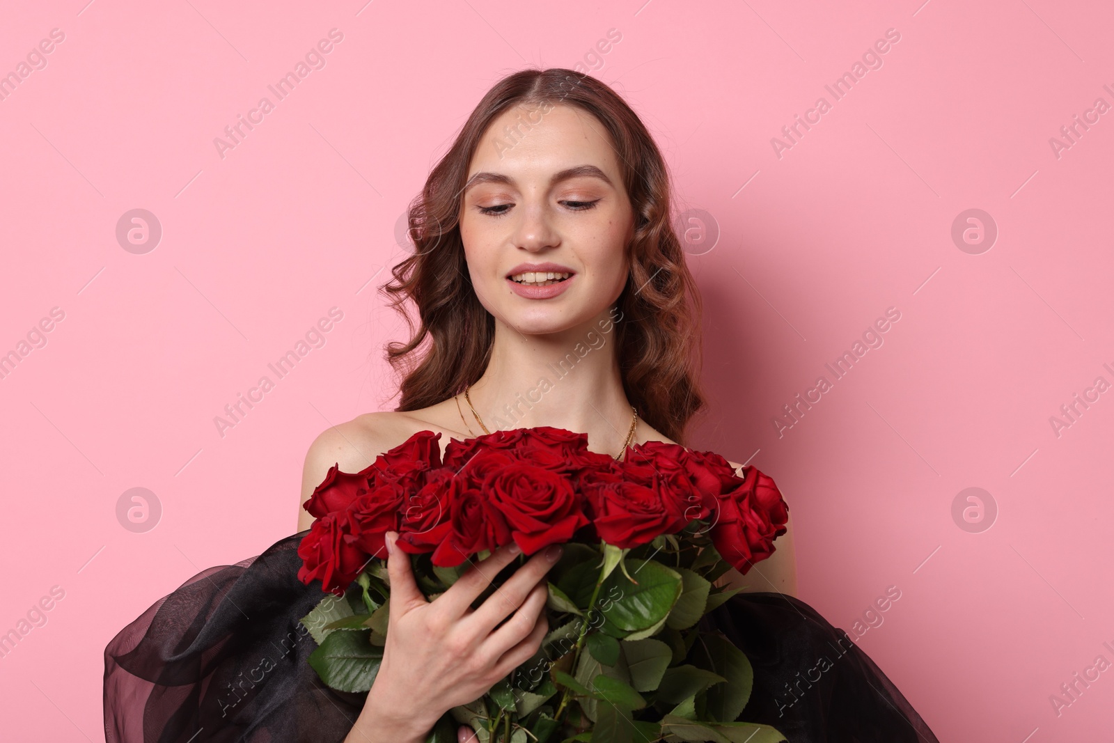 Photo of Smiling woman with bouquet of roses on pink background