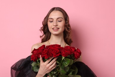 Smiling woman with bouquet of roses on pink background