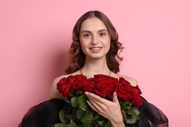 Photo of Smiling woman with bouquet of roses on pink background