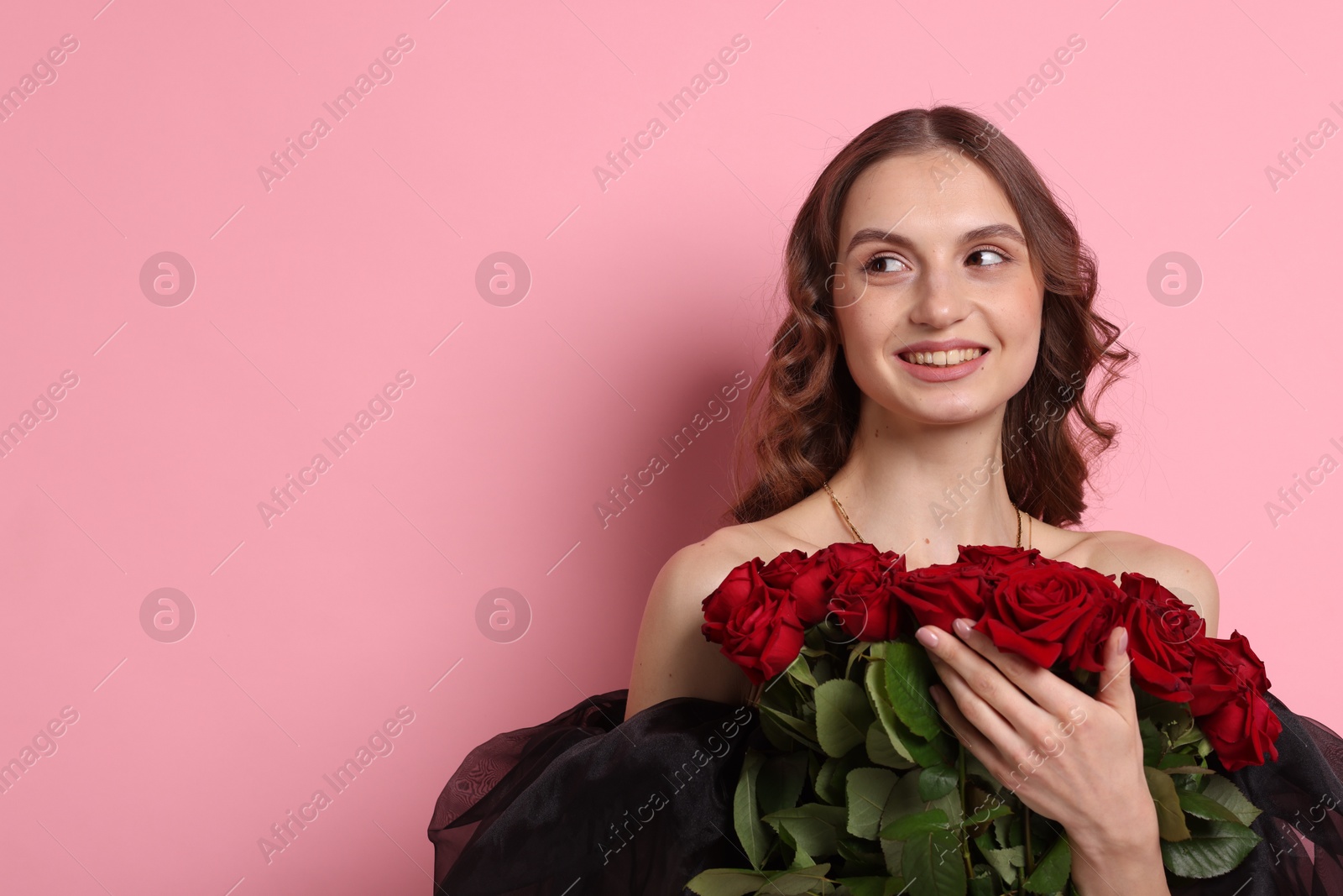 Photo of Smiling woman with bouquet of roses on pink background. Space for text