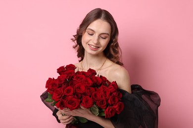 Photo of Smiling woman with bouquet of roses on pink background