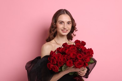 Photo of Smiling woman with bouquet of roses on pink background