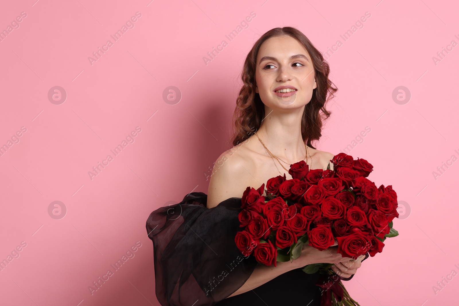 Photo of Smiling woman with bouquet of roses on pink background. Space for text