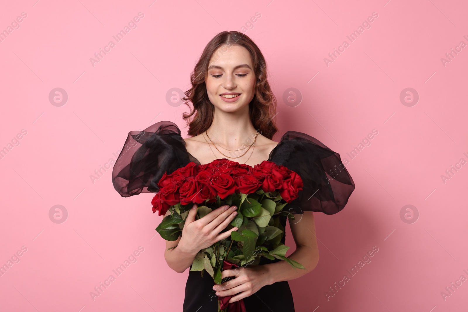 Photo of Smiling woman with bouquet of roses on pink background