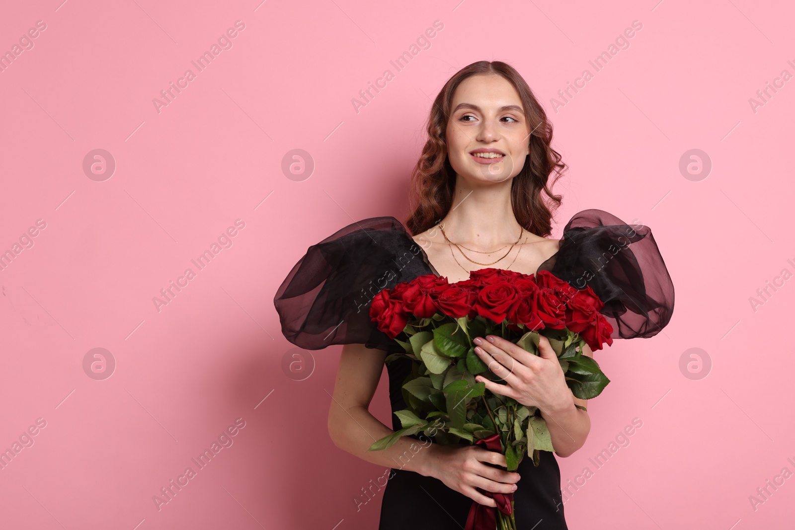 Photo of Smiling woman with bouquet of roses on pink background. Space for text