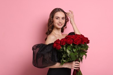 Smiling woman with bouquet of roses on pink background