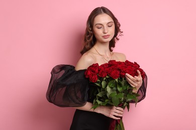 Beautiful woman with bouquet of roses on pink background