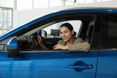 Photo of Happy woman inside new car in salon