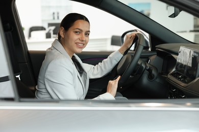 Photo of Happy woman inside new car in salon