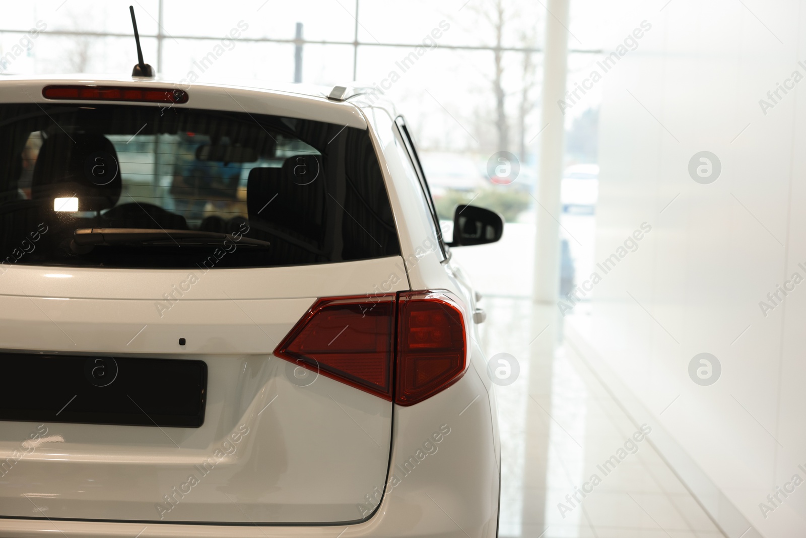 Photo of New modern white car in salon, space for text