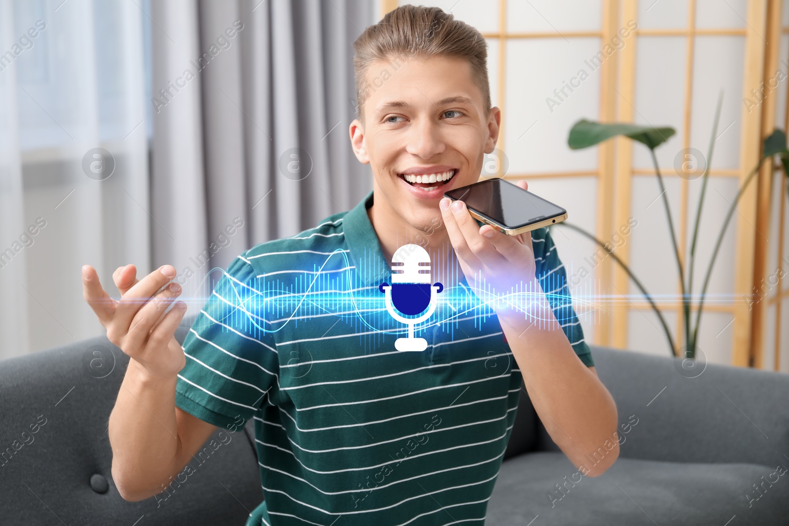 Image of Young man recording voice message via smartphone at home. Illustration of microphone and sound waves