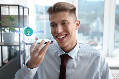 Image of Young man recording voice message via smartphone in office. Illustration of microphone and sound waves