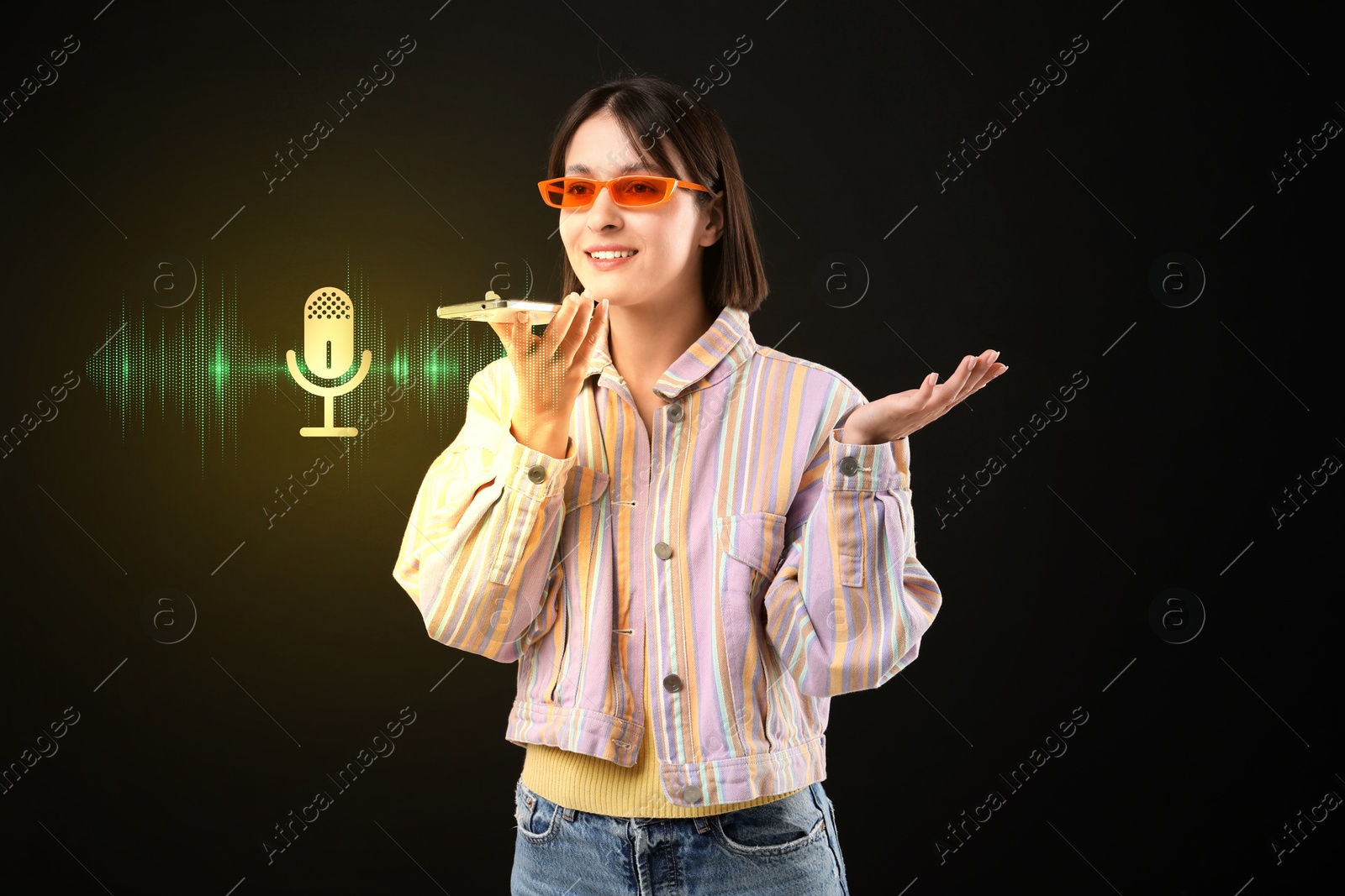 Image of Young woman recording voice message via smartphone on black background. Illustration of microphone and sound waves