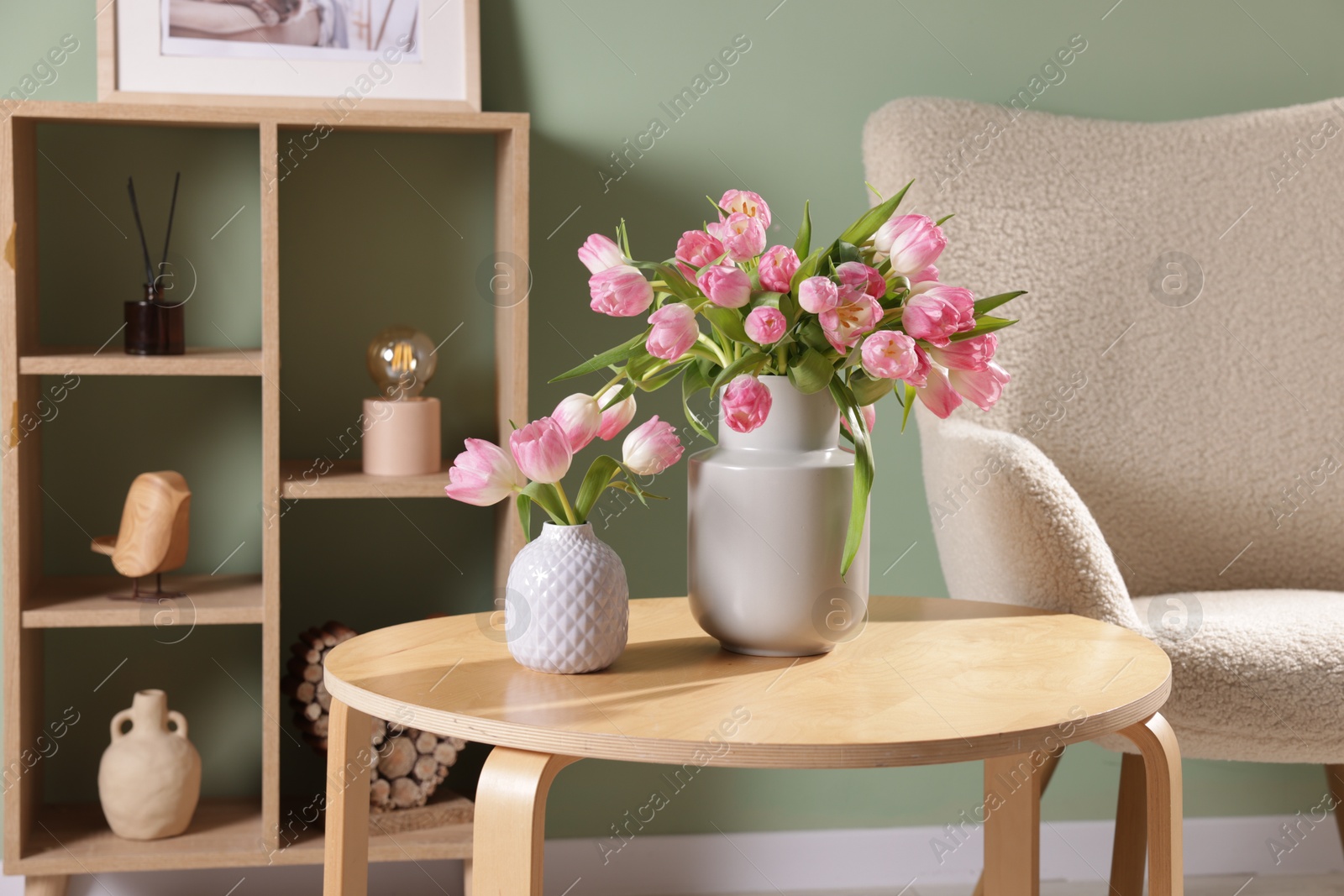 Photo of Beautiful tulips in vases on coffee table indoors