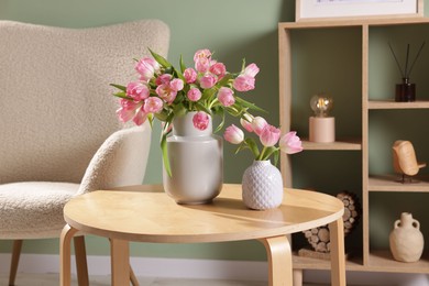 Photo of Beautiful tulips in vases on coffee table indoors