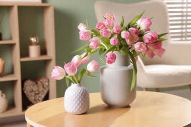 Photo of Beautiful tulips in vases on coffee table indoors