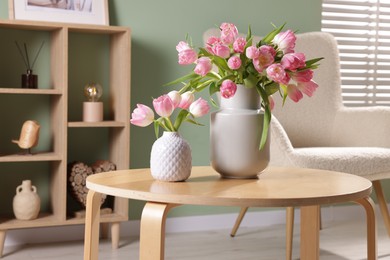 Photo of Beautiful tulips in vases on coffee table indoors