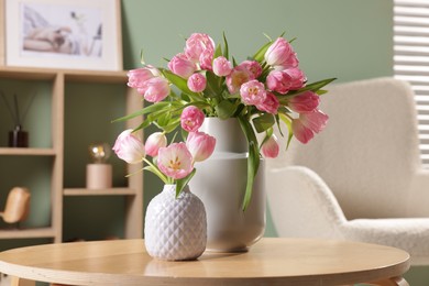 Photo of Beautiful tulips in vases on coffee table indoors, closeup