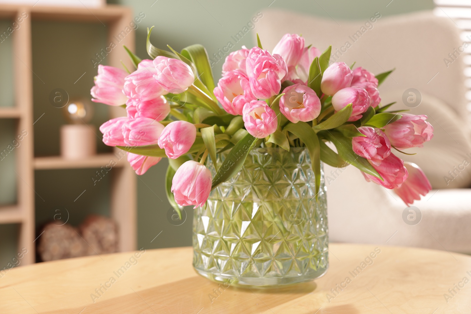 Photo of Beautiful tulips in vase on wooden table indoors, closeup