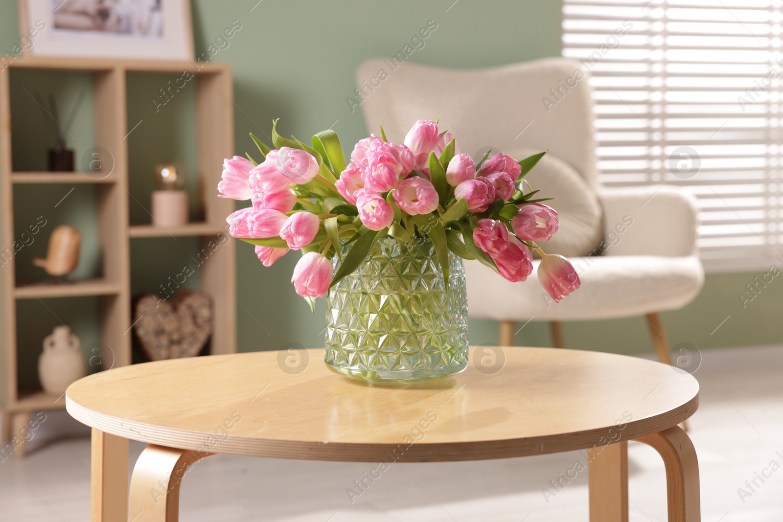 Photo of Beautiful tulips in vase on coffee table indoors