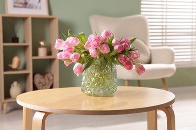 Photo of Beautiful tulips in vase on coffee table indoors