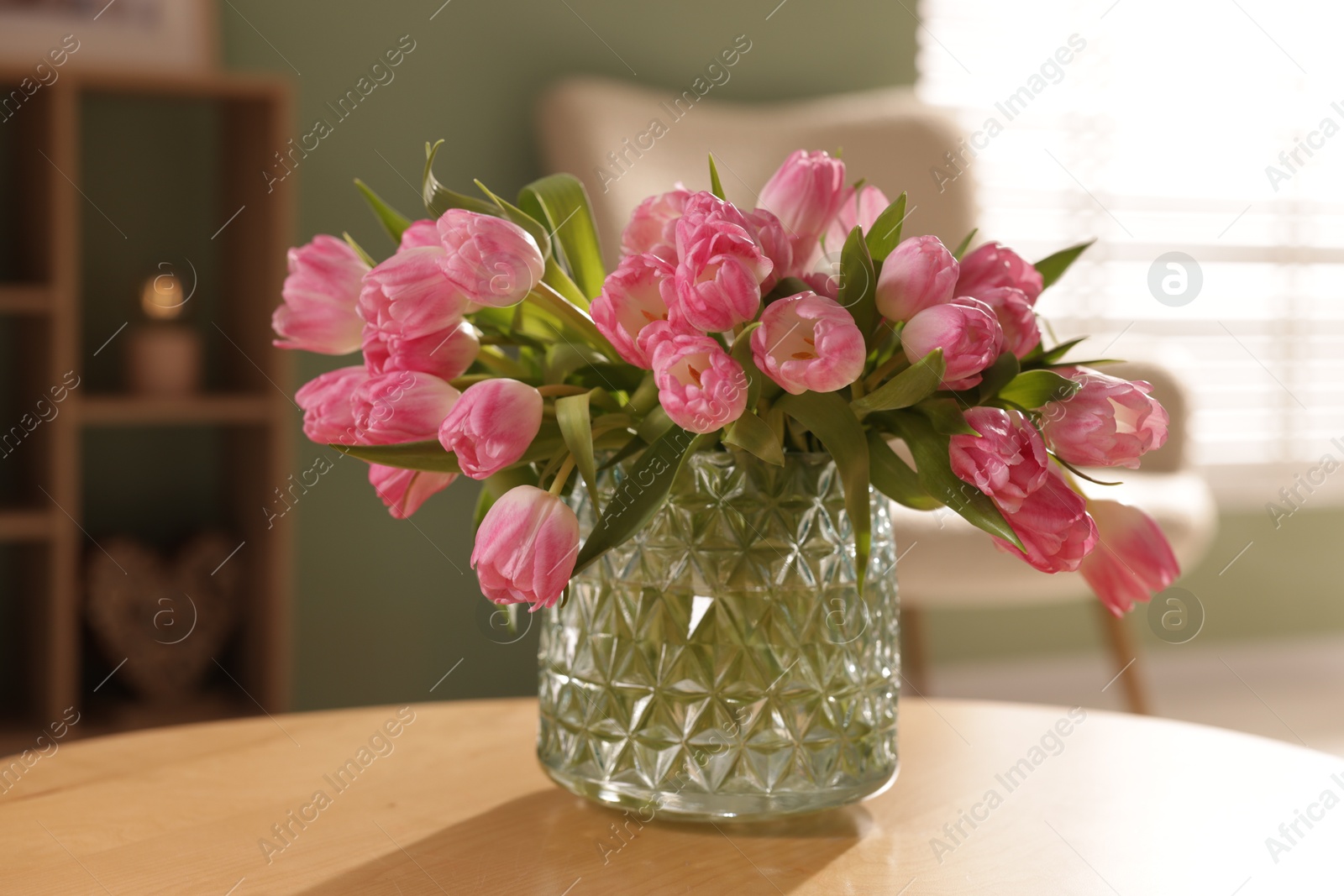 Photo of Beautiful tulips in vase on wooden table indoors, closeup