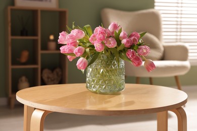 Photo of Beautiful tulips in vase on coffee table indoors