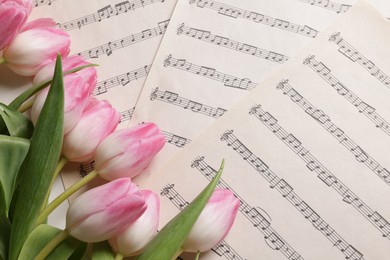 Photo of Beautiful tulips on sheets with music notes, top view