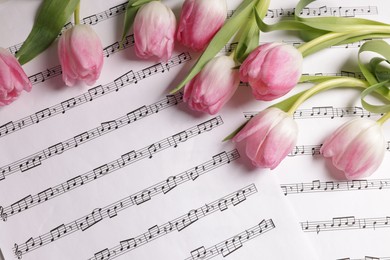 Beautiful tulips on sheets with music notes, top view