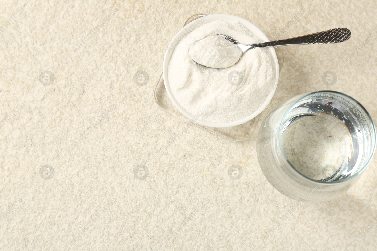 Collagen powder in bowl, spoon and glass of water on light textured table, flat lay. Space for text Photo of Collagen powder in bowl, spoon and glass of water on light textured table, flat lay. Space for text