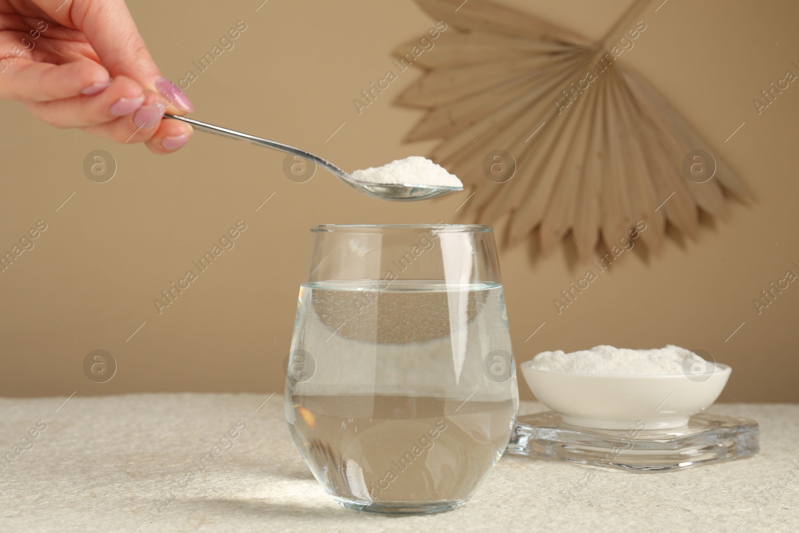 Woman adding collagen powder into glass with water at light textured table against beige background, closeup Photo of Woman adding collagen powder into glass with water at light textured table against beige background, closeup
