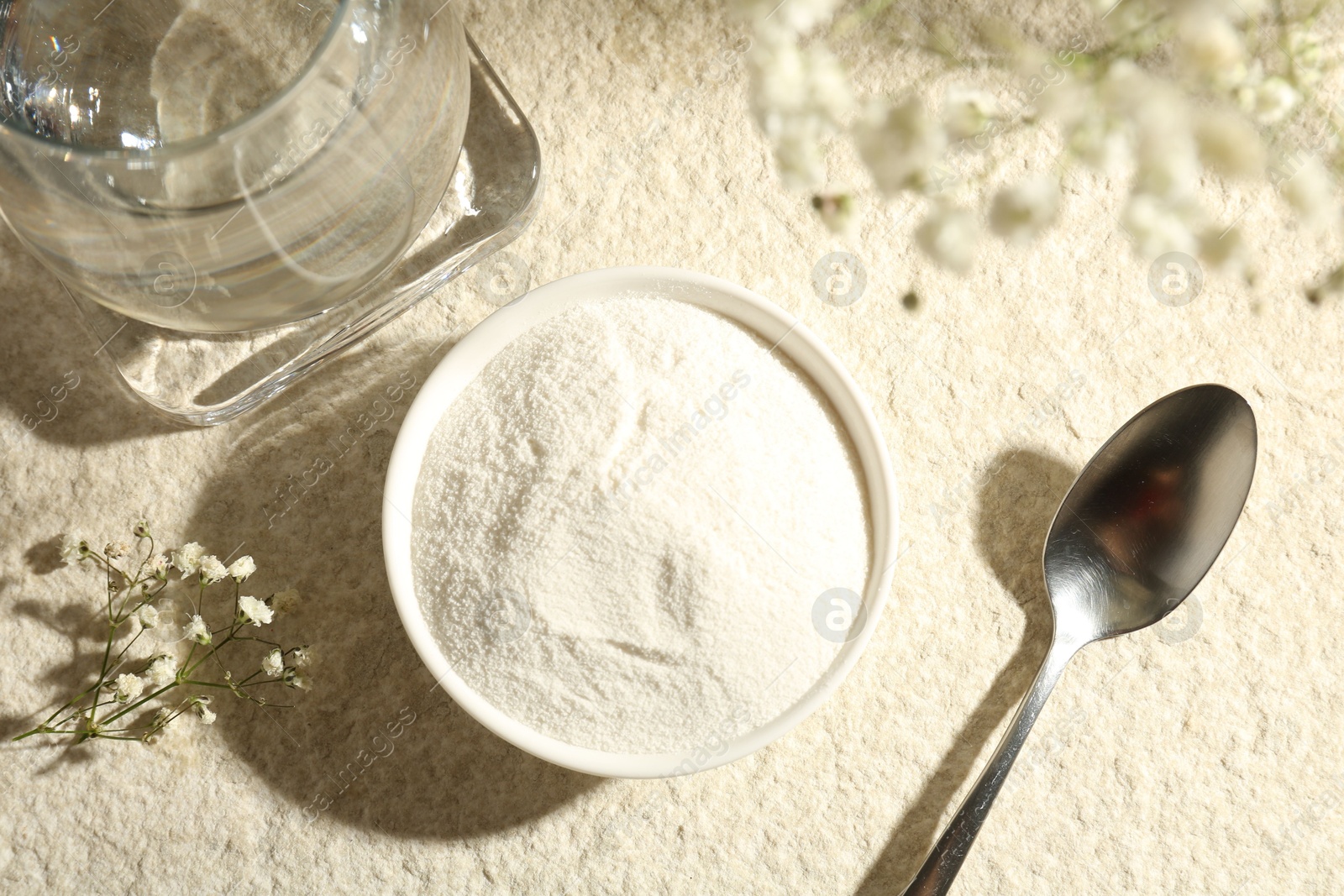 Collagen powder in bowl, spoon, glass of water and gypsophila branches on light textured table, flat lay Photo of Collagen powder in bowl, spoon, glass of water and gypsophila branches on light textured table, flat lay
