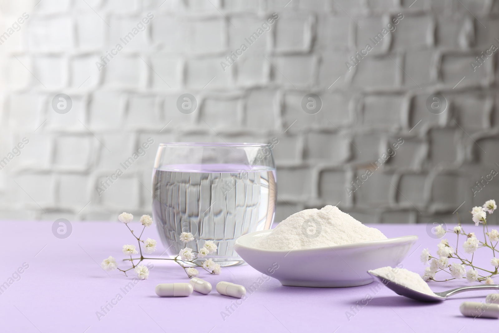 Collagen powder in bowl, spoon, pills, glass of water and gypsophila flowers on violet table indoors Photo of Collagen powder in bowl, spoon, pills, glass of water and gypsophila flowers on violet table indoors