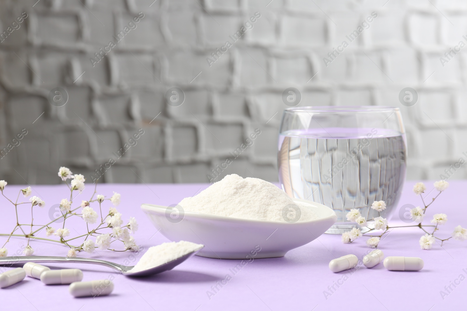 Collagen powder in bowl, spoon, pills, glass of water and gypsophila flowers on violet table indoors Photo of Collagen powder in bowl, spoon, pills, glass of water and gypsophila flowers on violet table indoors