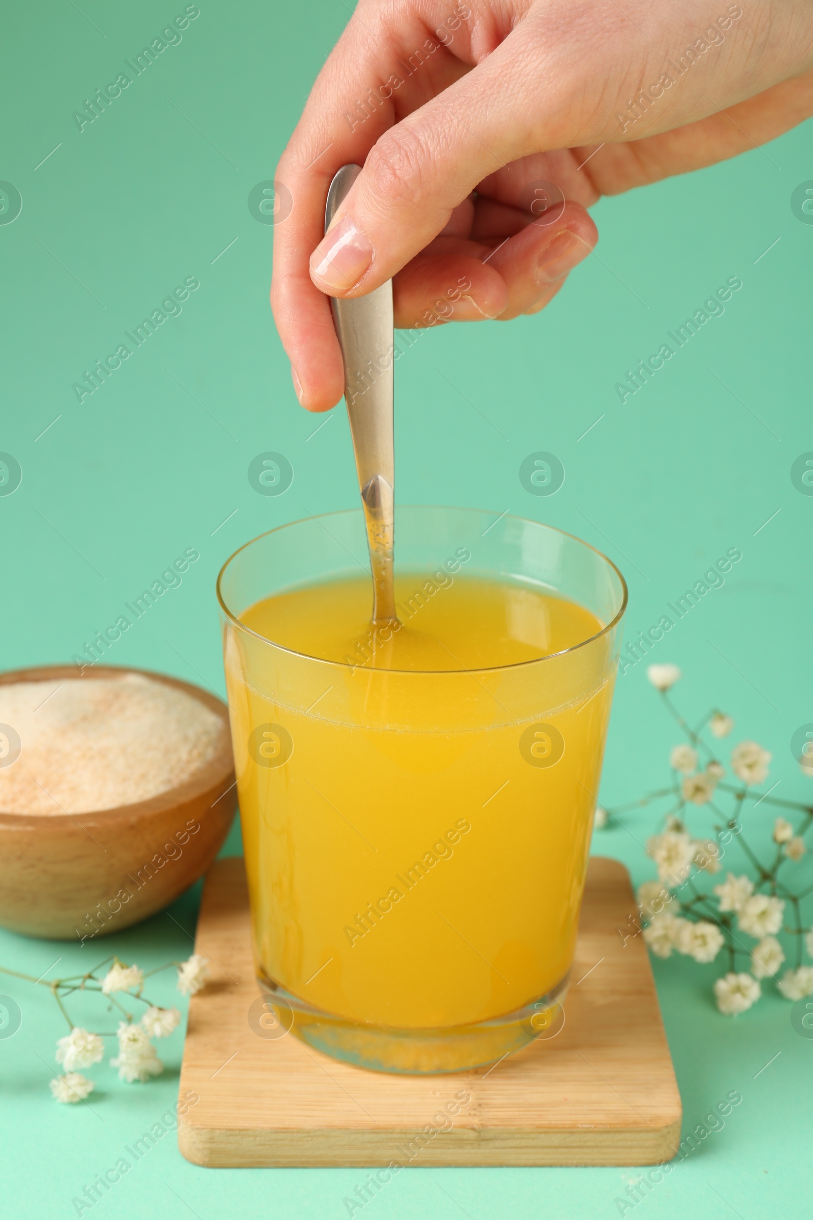 Woman stirring collagen powder in water on turquoise background, closeup Photo of Woman stirring collagen powder in water on turquoise background, closeup