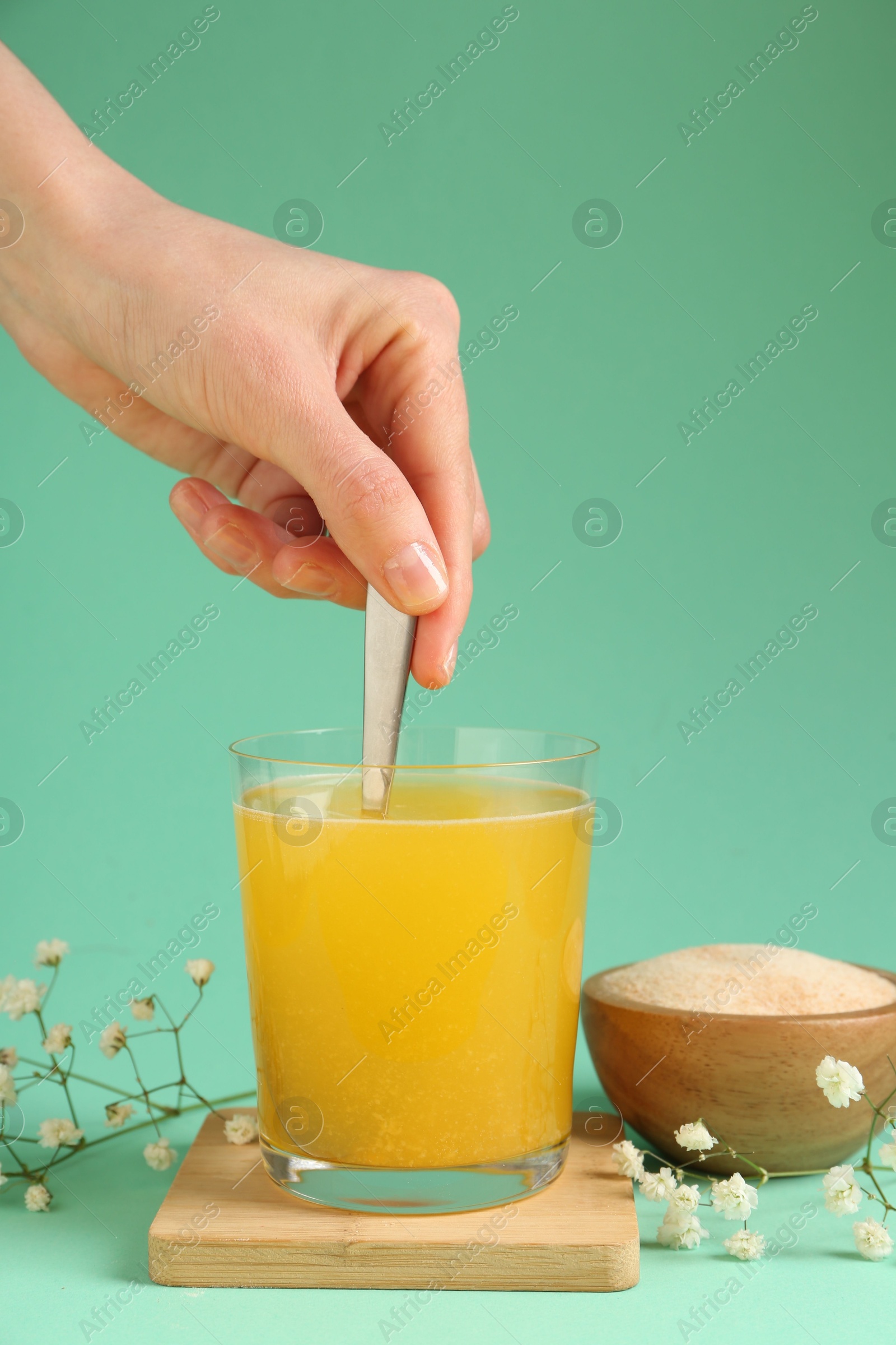 Woman stirring collagen powder in water on turquoise background, closeup Photo of Woman stirring collagen powder in water on turquoise background, closeup