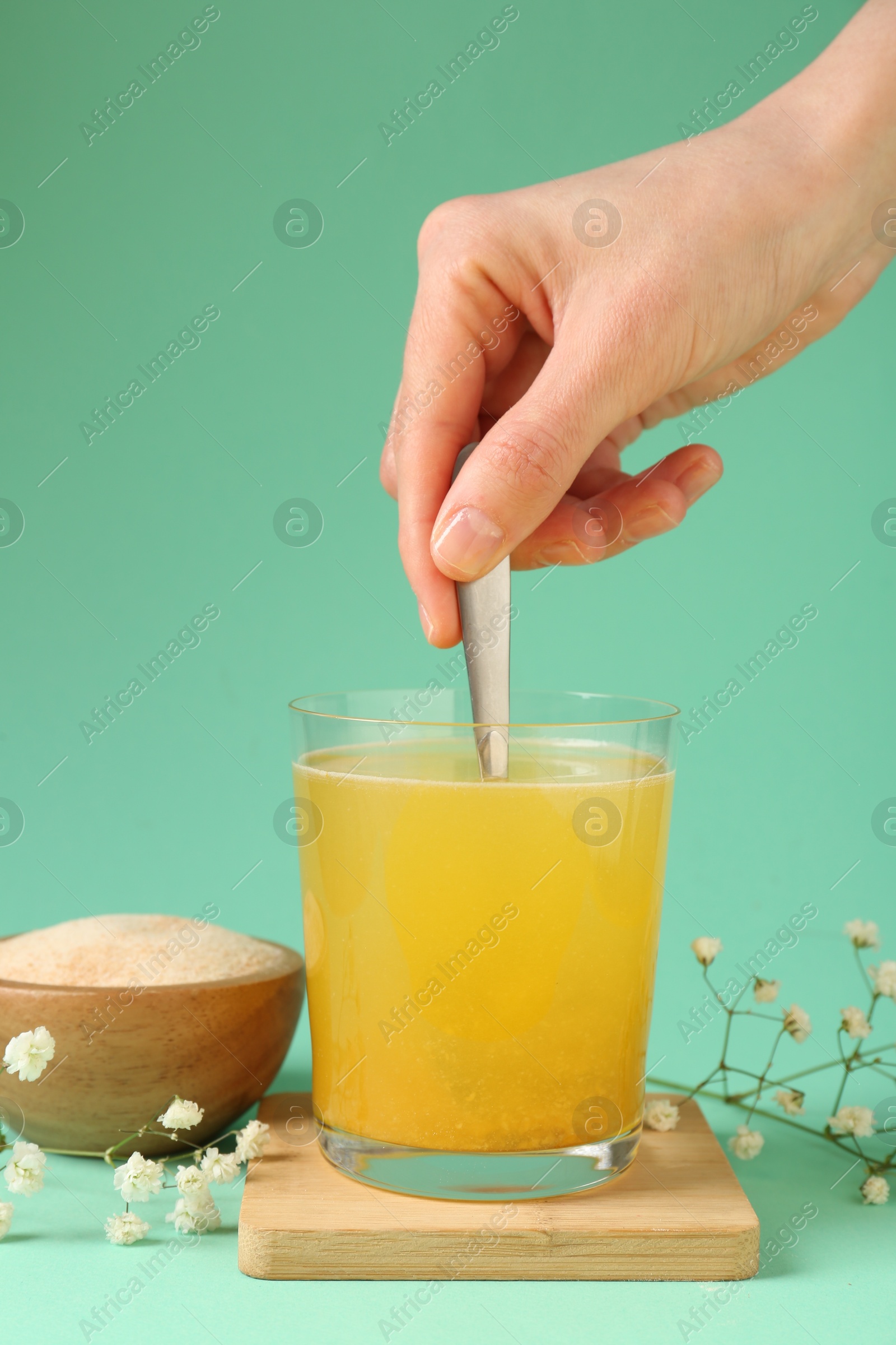 Woman stirring collagen powder in water on turquoise background, closeup Photo of Woman stirring collagen powder in water on turquoise background, closeup