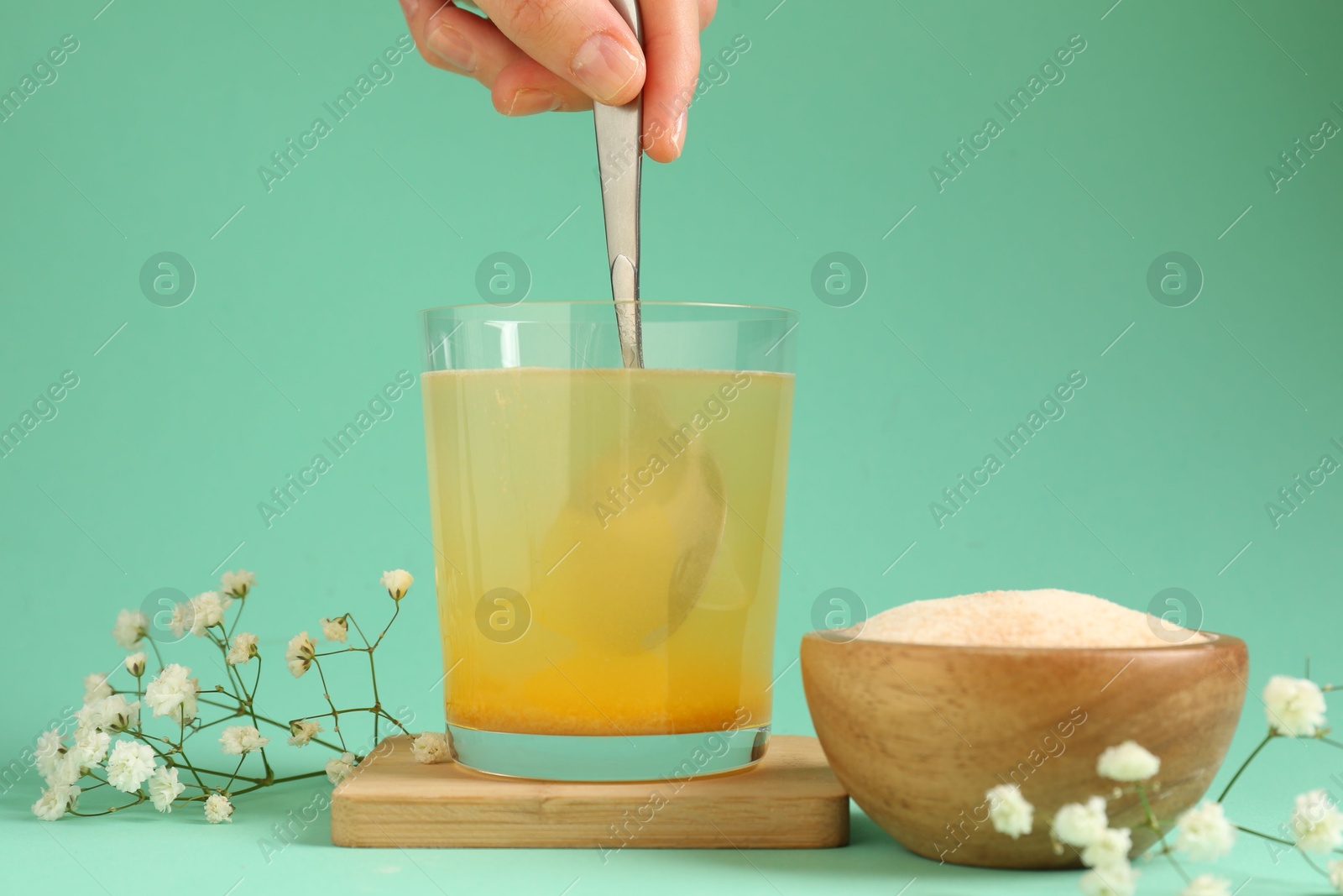 Woman stirring collagen powder in water on turquoise background, closeup Photo of Woman stirring collagen powder in water on turquoise background, closeup