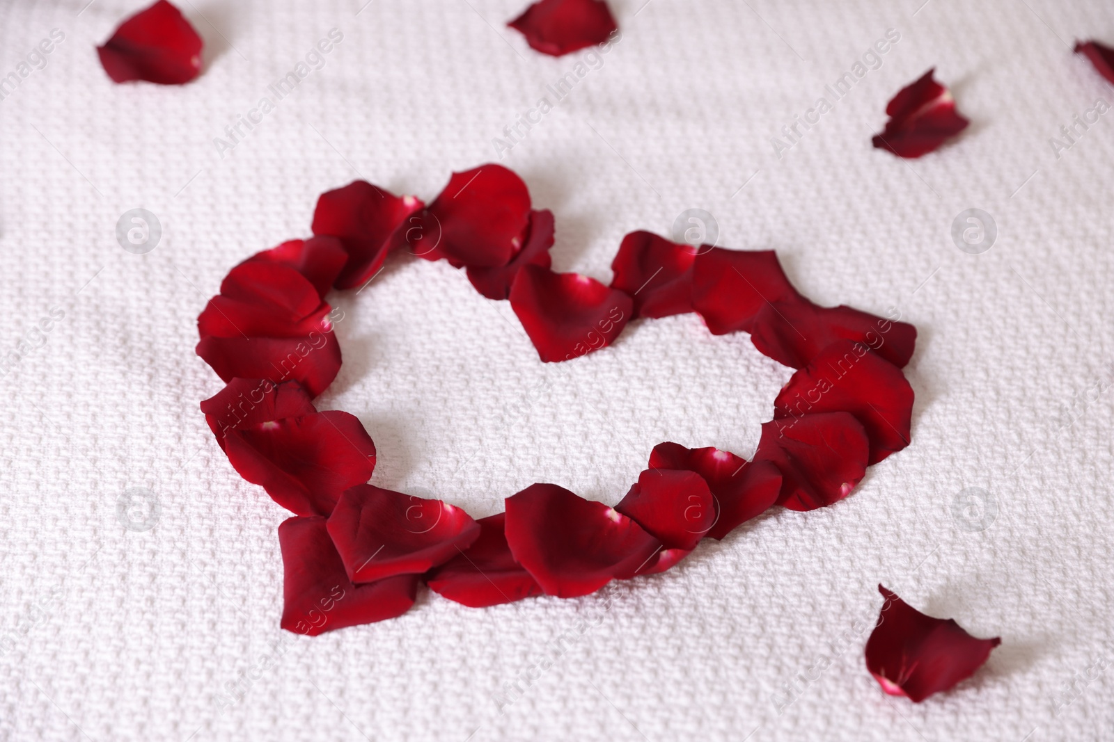 Heart made with beautiful rose petals on bed, closeup Photo of Heart made with beautiful rose petals on bed, closeup