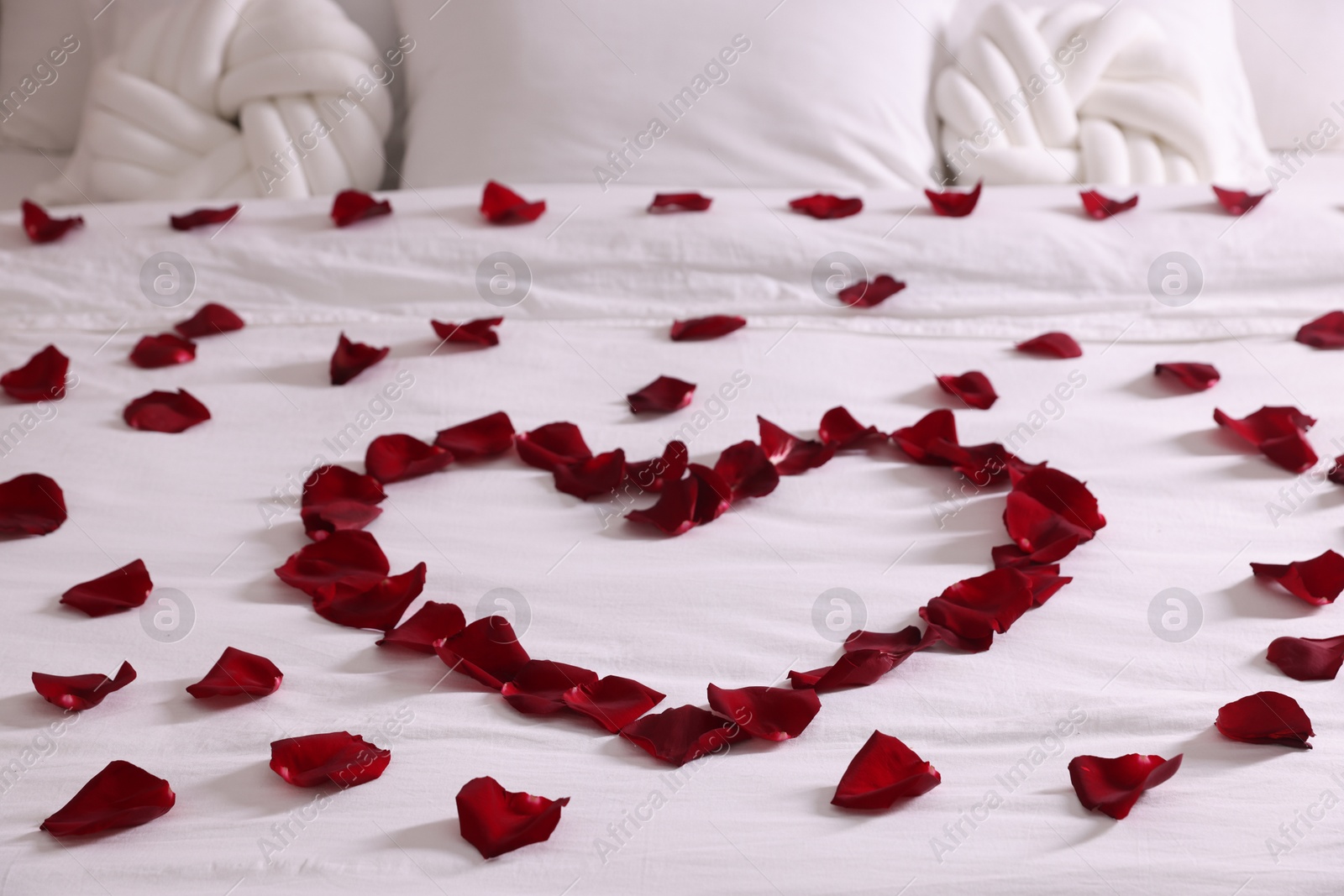 Heart made with beautiful rose petals on bed Photo of Heart made with beautiful rose petals on bed