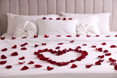 Photo of Heart made with beautiful rose petals on bed